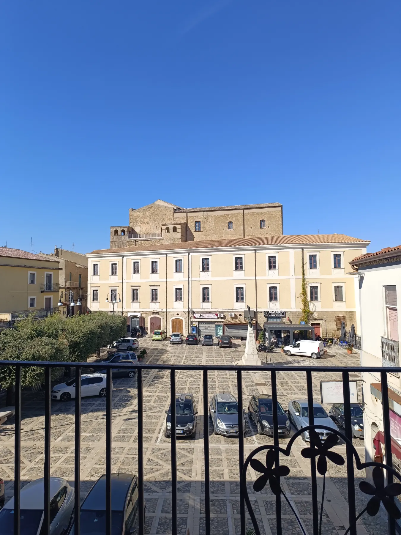 Vue sur une place avec des bâtiments historiques à Tricarico au soleil.